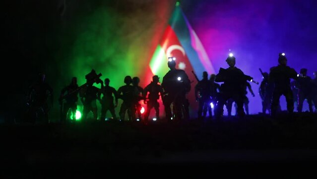 Azeri army concept. Silhouette of armed soldiers against Azerbaijani flag. Creative artwork decoration. Military silhouettes fighting scene dark toned foggy background. Selective focus