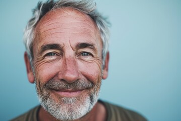 Portrait of senior man with grey hair and beard on blue background