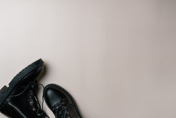 Black boots on beige background. Copy space