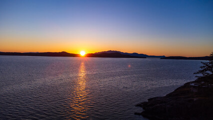 Sunset over Thormanby Island. Sun dipping behind the low point between two mountains. 