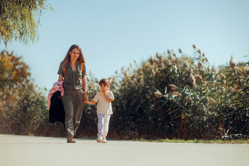 Mother and Daughter Walking Together in a Natural Park. Happy family relaxing on vacation in a...