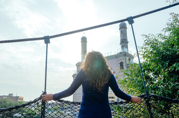 Woman gazing at mosque from balcony