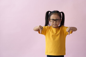 Fototapeta premium Little girl wearing glasses suffering from headache, hopeless, angry, and stressed because of pain and migraine, hands on head, tired, standing on pink copy space background.