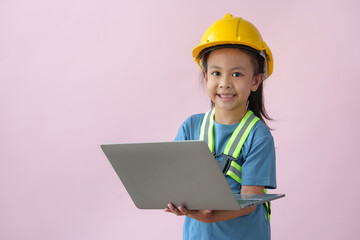 Young Asian girls' future dream careers as engineers and architects, wearing yellow helmets and fluorescent harnesses for work, stand holding notebook computers, smiling happily.