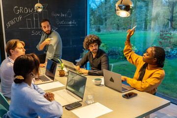 A group of multiethnic entrepreneurs engages in an inspiring brainstorming session in a well-lit...