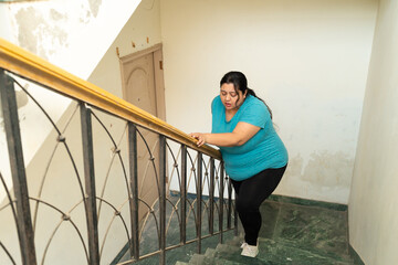 Overweight fat indian woman feeling unwell, not able to breath while climbing stairs. Healthcare...