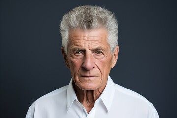 Portrait of a senior man with grey hair and white shirt.