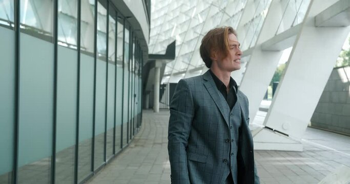 Serious businessman is feeling very upset over failure of important project. Man reacts emotionally to this upset while standing outside office. Man is deeply upset by realization that idea has failed