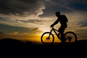 Fototapeta premium Silhouetted figure with mountain bike against dramatic sunset backdrop