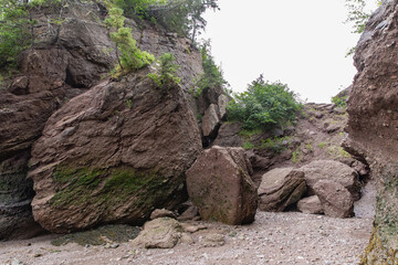 haute falaise érodée avec des grosses roches et des arbres au sommet lors d'une journée ennuagée d'été