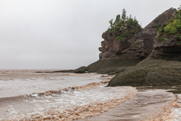 Fototapeta na wymiar vue sur le bord de l'eau lors d'une marée montante avec un rocher et de la verdure au top