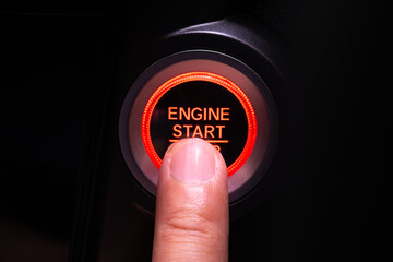 The driver's hand is pressing the car start button. Concept of transportation and technology - obrazy, fototapety, plakaty