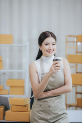 Small business entrepreneurSME Freelance Asian woman working at home using laptop computer and boxes Cheerful successful Asian woman Online marketing and SME delivery ideas