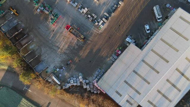 Overhead drone aerial footage of industrial, commercial, yard. Storage facility with morning views of workers and vehicle moving around with men at work. Containers and chemical plant machinery