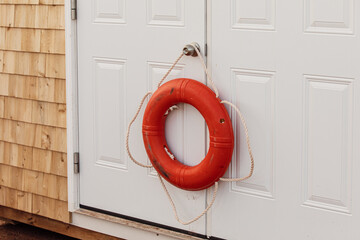 vue sur une bouée de sauvetage orange accrochée à la poignée d'une porte peinte en blanc