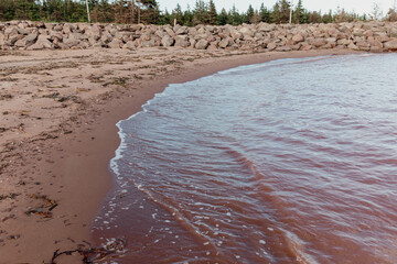 vue sur une petite baie avec du sable rouge en été et une vague qui vient s'échouer