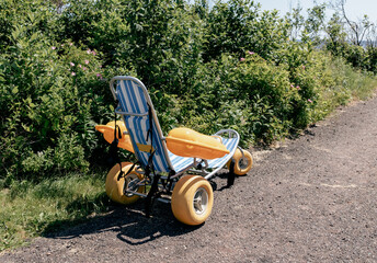 chaise de plage roulante avec des grosses roues jaunes et des flotteurs jaune en été 