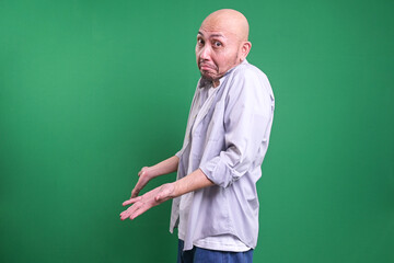 Bald Man Gesturing Confuse and Showing Helpless Gesture Shrugging Shoulder Isolated on Green...