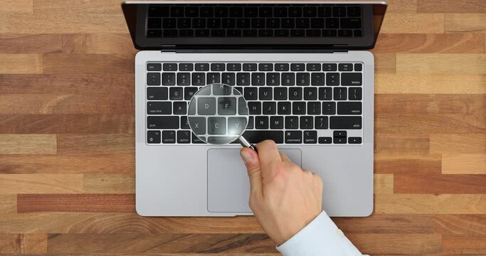 Checking a laptop keyboard with a magnifying glass, top view