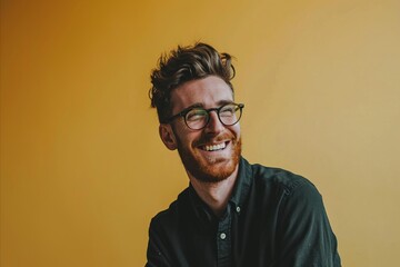 Portrait of a young man with red beard and glasses on yellow background