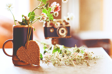 Vintage style, analogue camera on the table and summer flowers in the cup with heart. Summer or...
