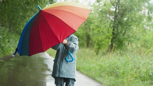 Child twirls umbrella in hands in park