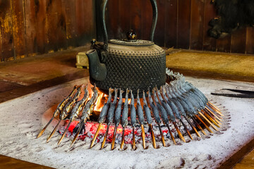 Fresh fish (Iwana) cooking over a wooden fire in a Japanese mountain hut