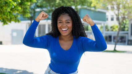 Cheering african american young adult woman in the city - obrazy, fototapety, plakaty