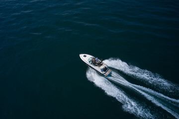 White boat fast movement on dark water, white trail on the water. Speed Boat with people in diagonal motion.