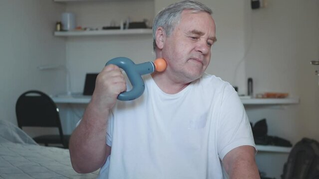 Man doing neck massage to himself with percussive vibrating massage gun.