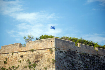 Greek waving flag on Koules Venetian Fortress at old Heraklion port Crete island destination Greece