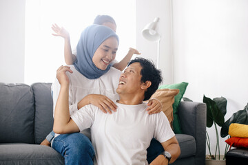 Muslim mom and father enjoying leisure time with their kid in living room.