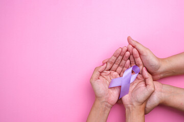 Hands Holding Purple Ribbon on Pink Background. Alzheimer's Disease, Epilepsy Awareness, World...