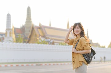 Traveler asian woman in her 30s, backpack slung over her shoulder, explores the intricate details...