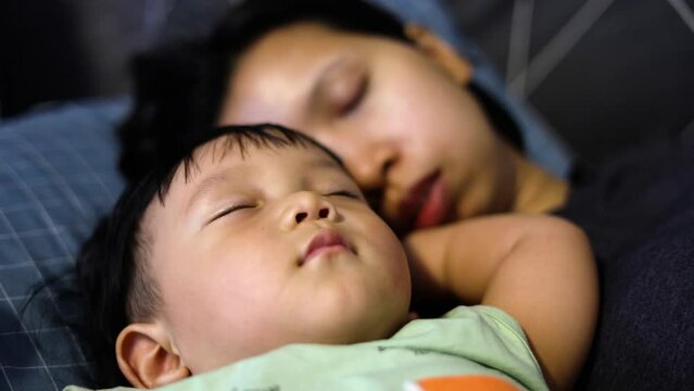 The baby sleeps with mom in bed. Cute boy and his mother lying in the bedroom. Sleep peacefully during the day. Safe sleep of the child and mother.
