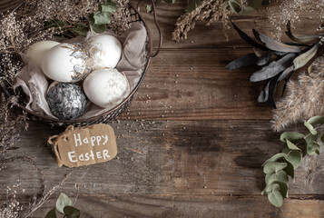 Easter composition with decorative eggs in a basket on a wooden surface copy space.