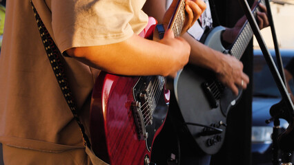 Close-up of a man playing guitar with another guitarist in the background. They are performing...