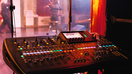 A mixer at a concert to adjust the sound levels of various elements, voices and instruments. Many knobs and sliders on the mixer.