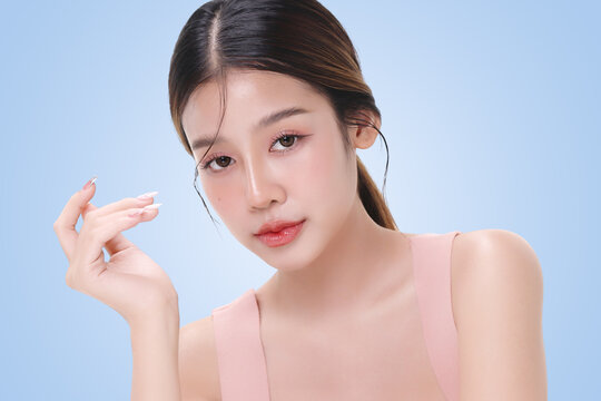 Close-up portrait of young Asian beautiful woman with K-beauty make up style and healthy and perfect skin isolated on light blue background for skincare commercial product advertising.