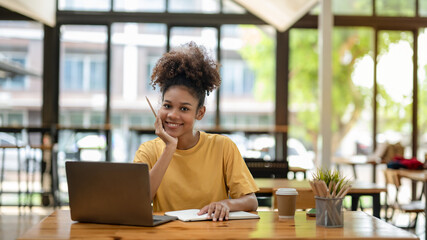 Smiling African American businesswoman, Young freelance business woman in casual look sitting work at coworks space and cafe.