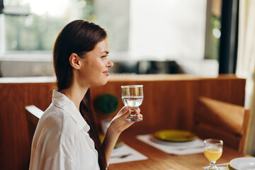 Happy woman enjoying a romantic dinner at home in a cozy dining room She is smiling ecstatically while sitting at a trendy dining table decorated with beautiful plates and a delicious homemade cake