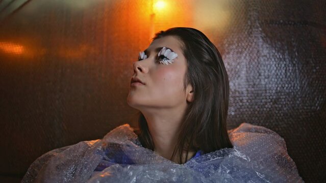 Fashion woman petal makeup surrounded by reflective bubble-wrap closeup. 
