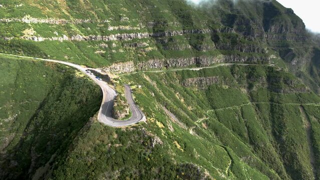 Madeira Lombo do Mouro viewpoint curved hairpin road aerial view across steep green terraced Madeira mountain slope