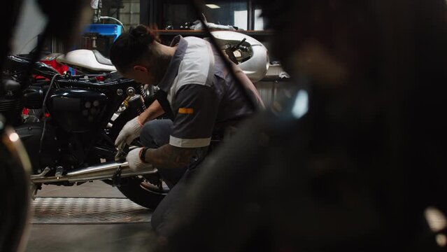Repairman examining broken clients motorcycle while working in garage