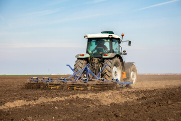 Powerful tractor cultivating fertile soil under clear skies, ready for sowing