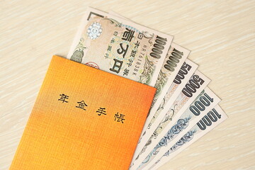 Japanese pension insurance book on table with yen money bills. Orange book for japan pensioners...