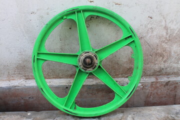 Green bicycle wheels propped against the wall

