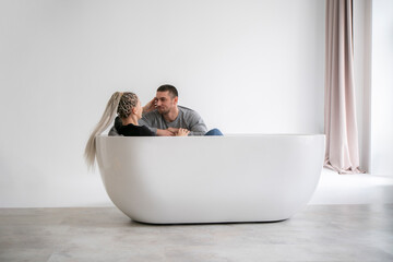 Man and Woman Engaging in Conversation While Sitting at Opposite Ends of a Modern Bathtub
