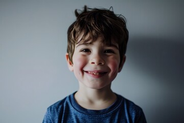 Portrait of a smiling little boy in a blue shirt on a gray background