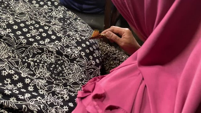 Indonesian old women making batik clothes. Batik is an Indonesian technique of wax-resist dyeing applied to the whole cloth. Closeup